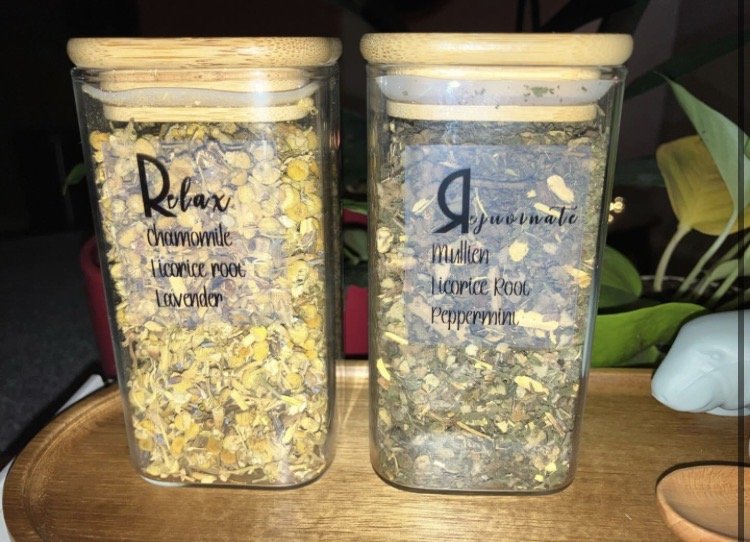Two glass jars of loose herbal tea on a wooden tray, labeled Relax and Rejuvenate