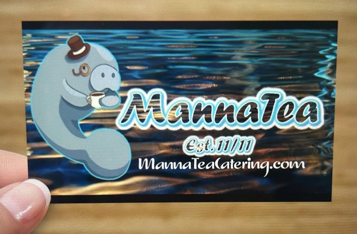 The Manna Tea logo: a manatee in a top hat and monocle holding a tea cup, over rippling blue water