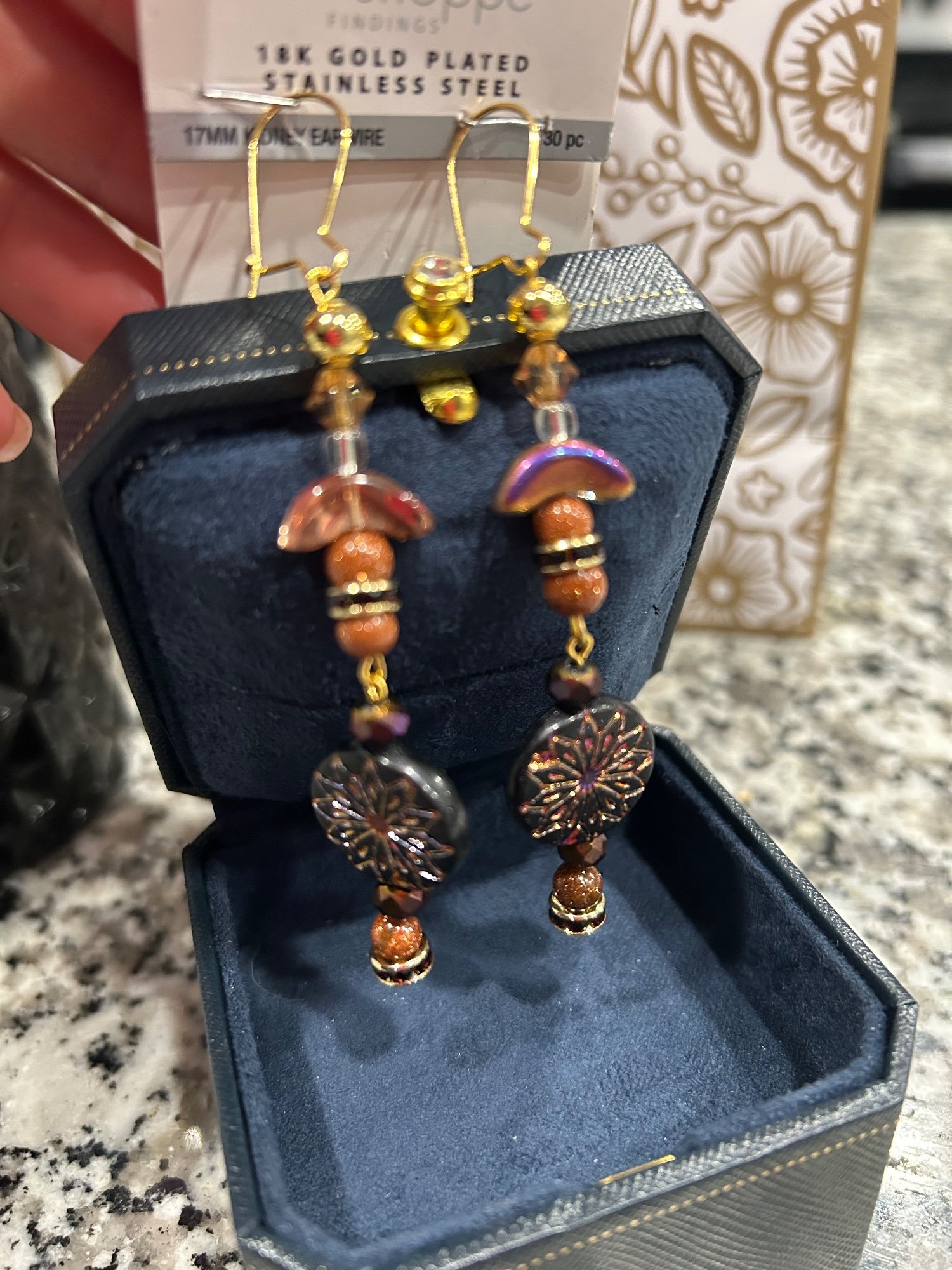 Gold and bronze beaded earrings in a navy jewelry box