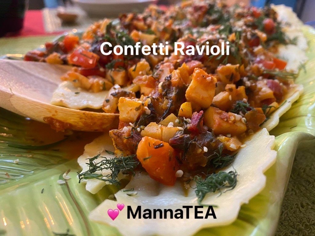 Confetti ravioli topped with diced squash, peppers, dill and sesame seeds on a green leaf-shaped plate