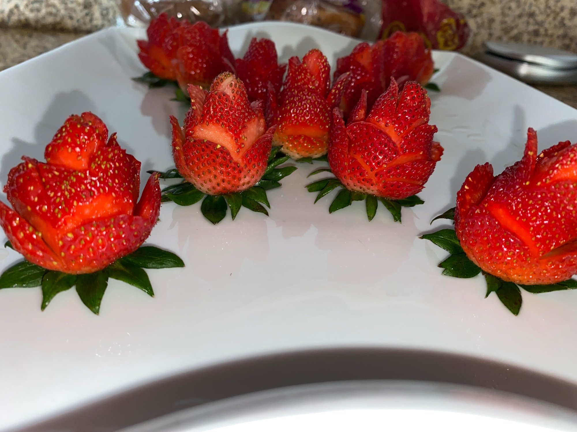 Strawberries carved into roses on a white plate