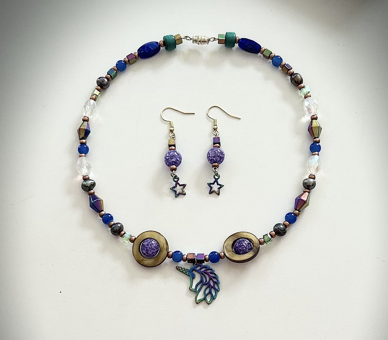 A blue and purple beaded necklace with a leaf charm and matching star earrings
